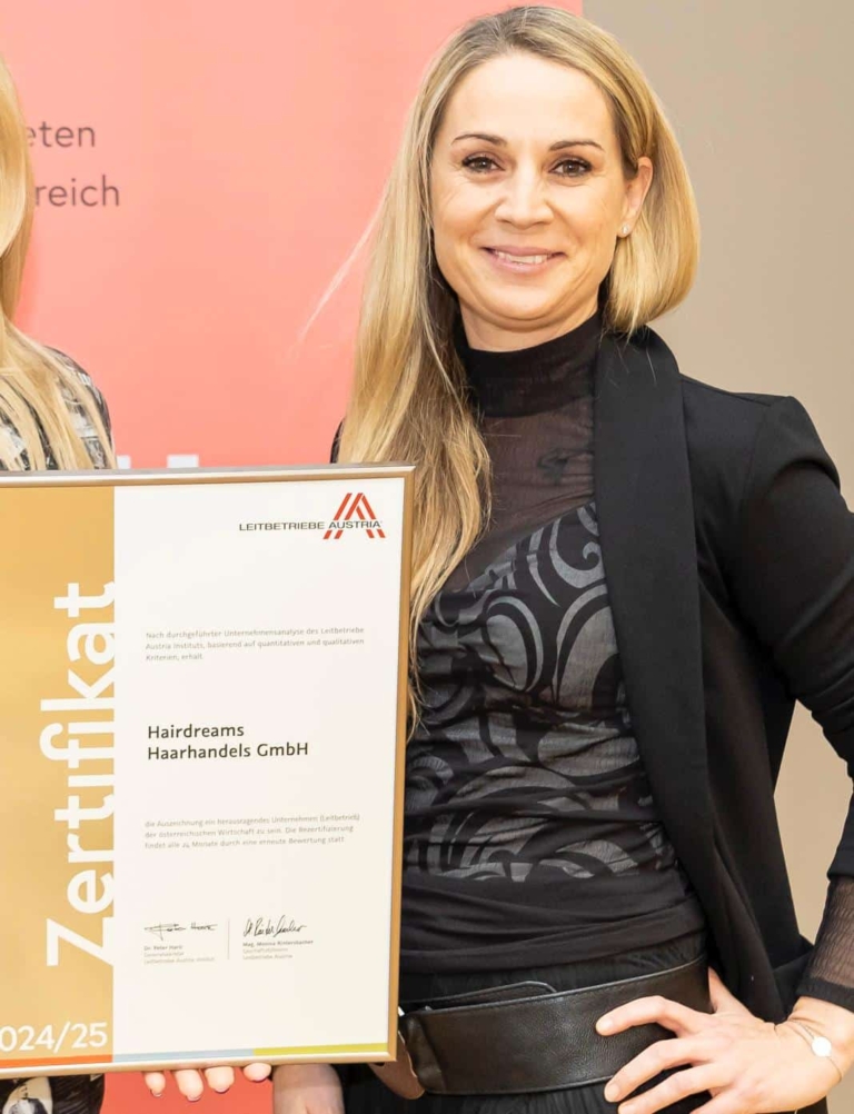 Nicole Höfer, a Hairdreams employee, holds an award from "Leitbetriebe Austria".